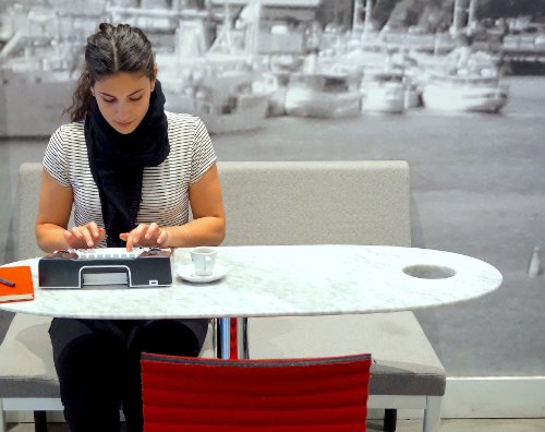 Jonge vrouw typt aan een tafeltje. Bron: Astrohaus